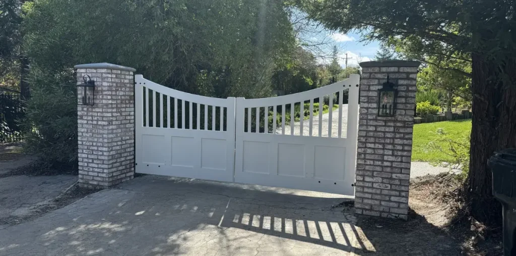 elegant wooden gate amidst blooming flowers and leafy trees in calm outdoor atmosphere under sunlight.